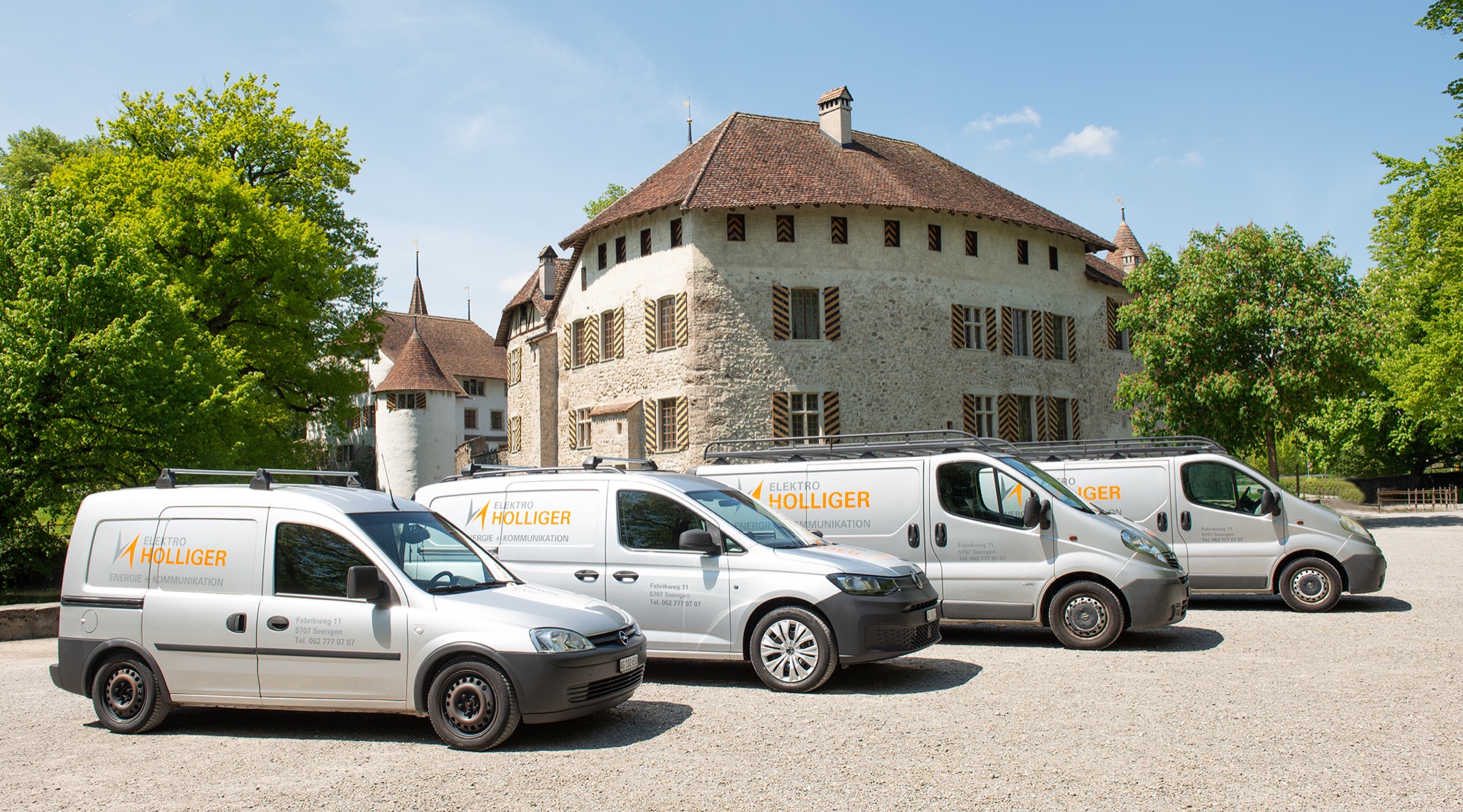 Vier Firmenwagen der Elektro Holliger AG mit Logo vor einem historischen Gebäude